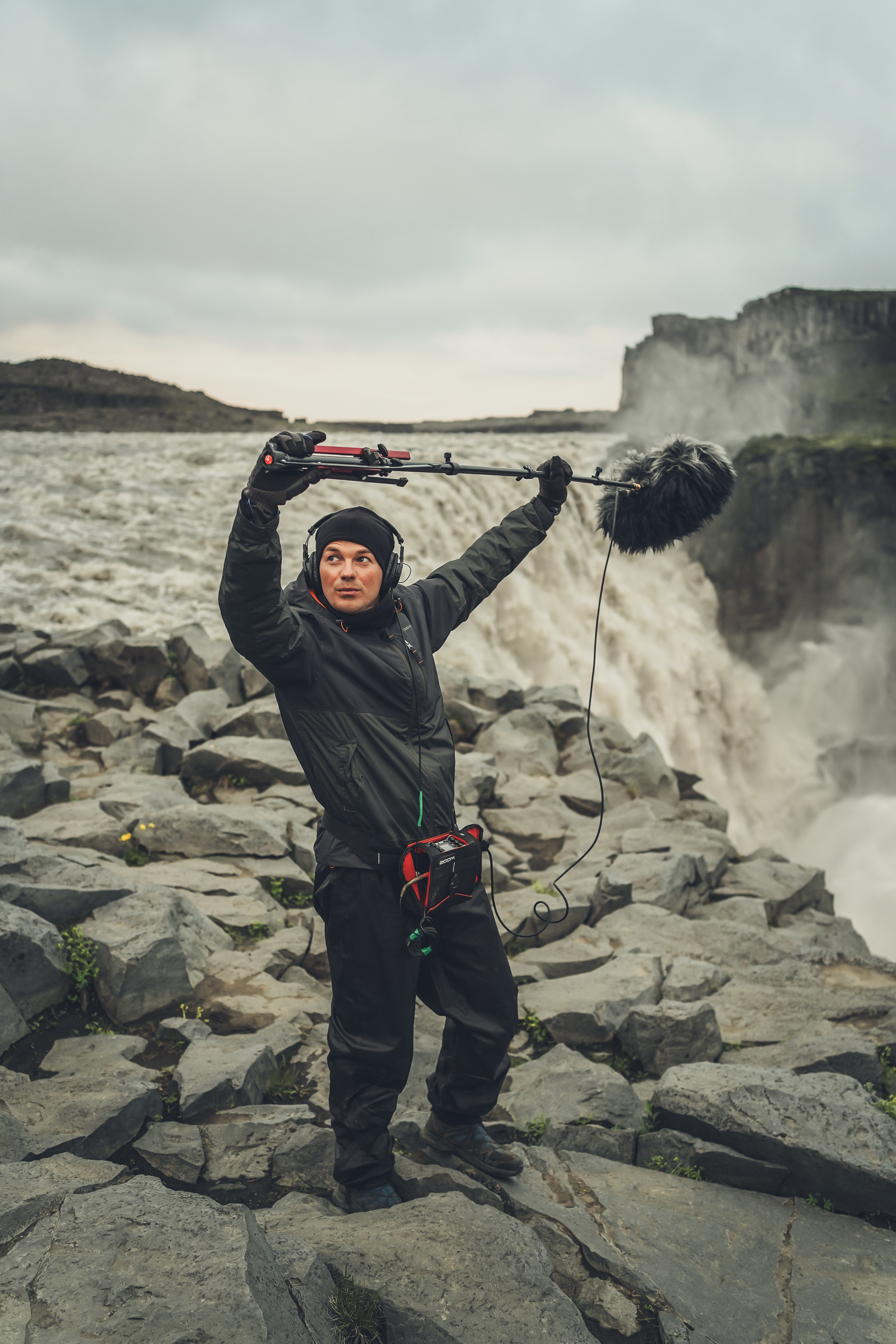 폭포 옆 악천후 환경에서 소리를 기록하는 field recordist