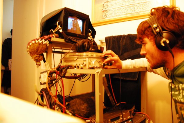 헤드폰을 착용하고 장비 앞의 노브를 조작하는 production sound mixer Jonathan Moran